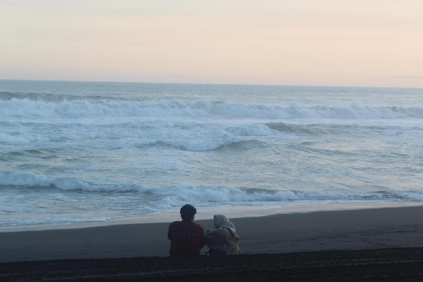 2 people were reading the Koran in the afternoon while looking at the beauty of the coast and sea photo
