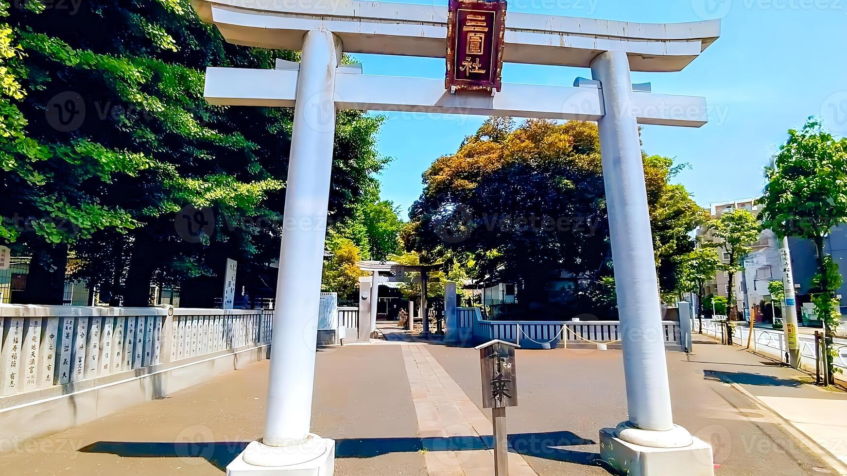 Mimeguri Shrine, a torii gate in the fresh greenery facing the street.Mimeguri Shrine is a shrine located in Mukojima, Sumida Ward, Tokyo, Japan. photo