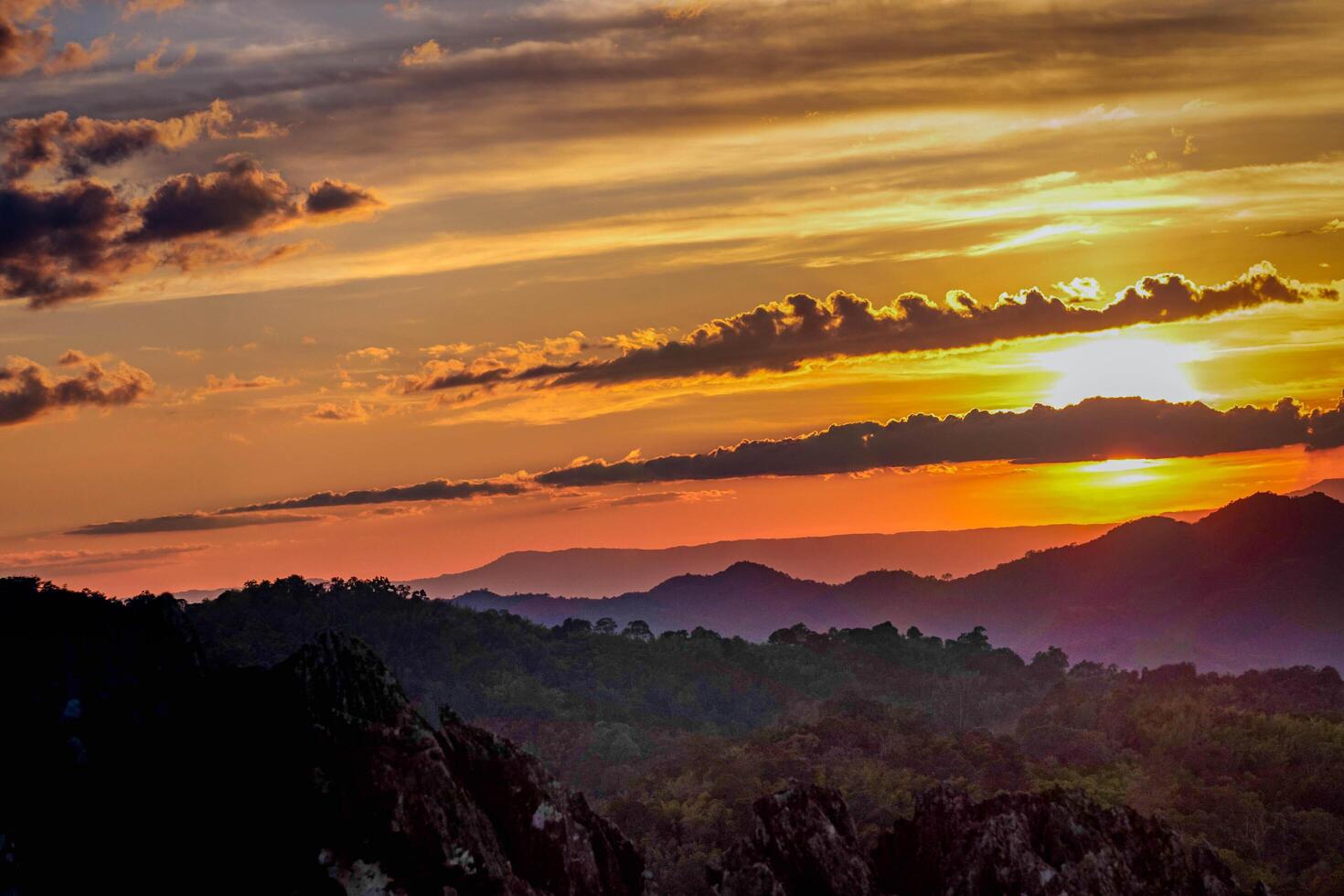 The stunning view from a tourist's standpoint as they go down a hill on a foggy trail with a hill and a background of a golden sky in Forest Park, Thailand. Rainforest. Bird's eye view. Aerial view. photo