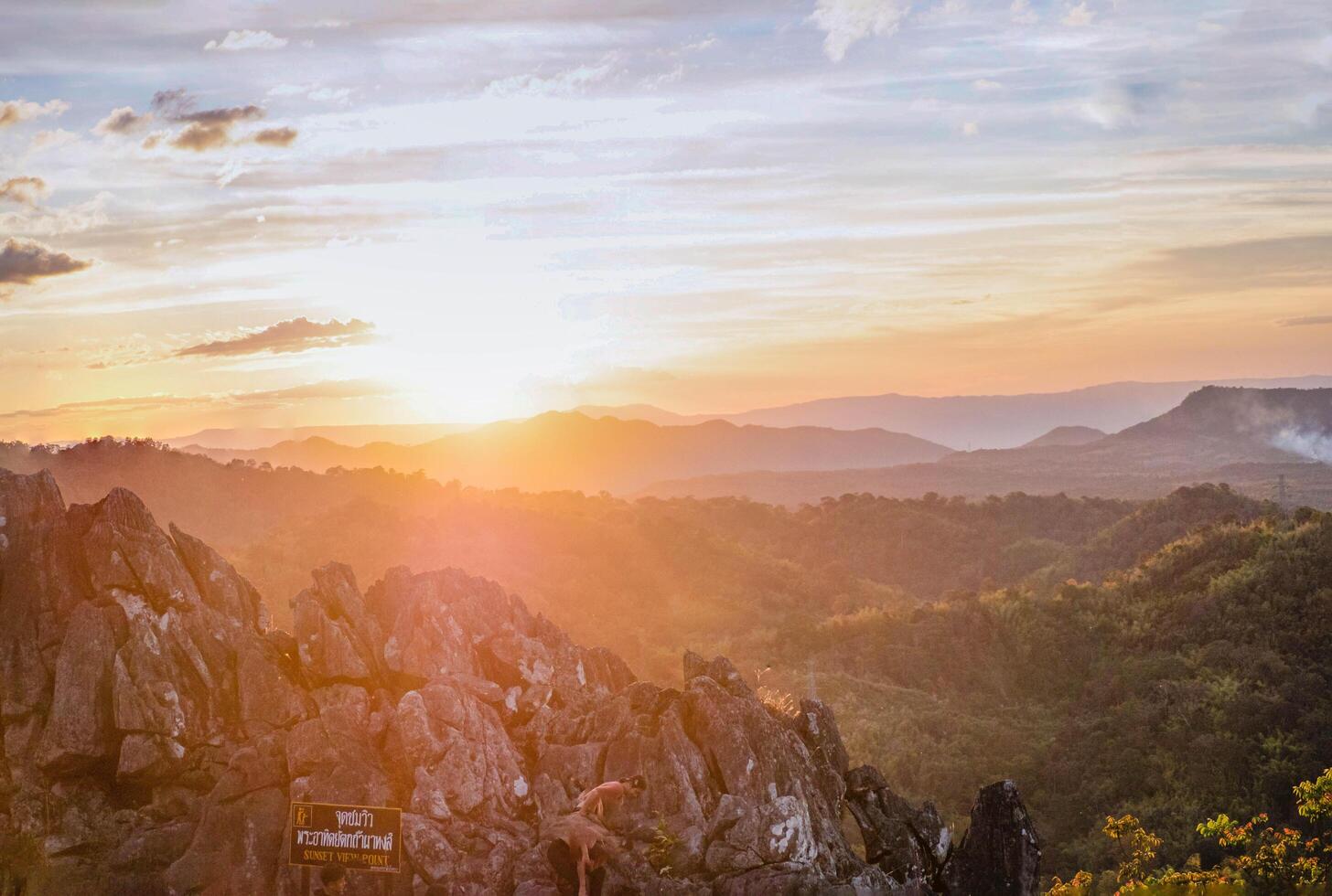 The stunning view from a tourist's standpoint as they go down a hill on a foggy trail with a hill and a background of a golden sky in Forest Park, Thailand. Rainforest. Bird's eye view. Aerial view. photo