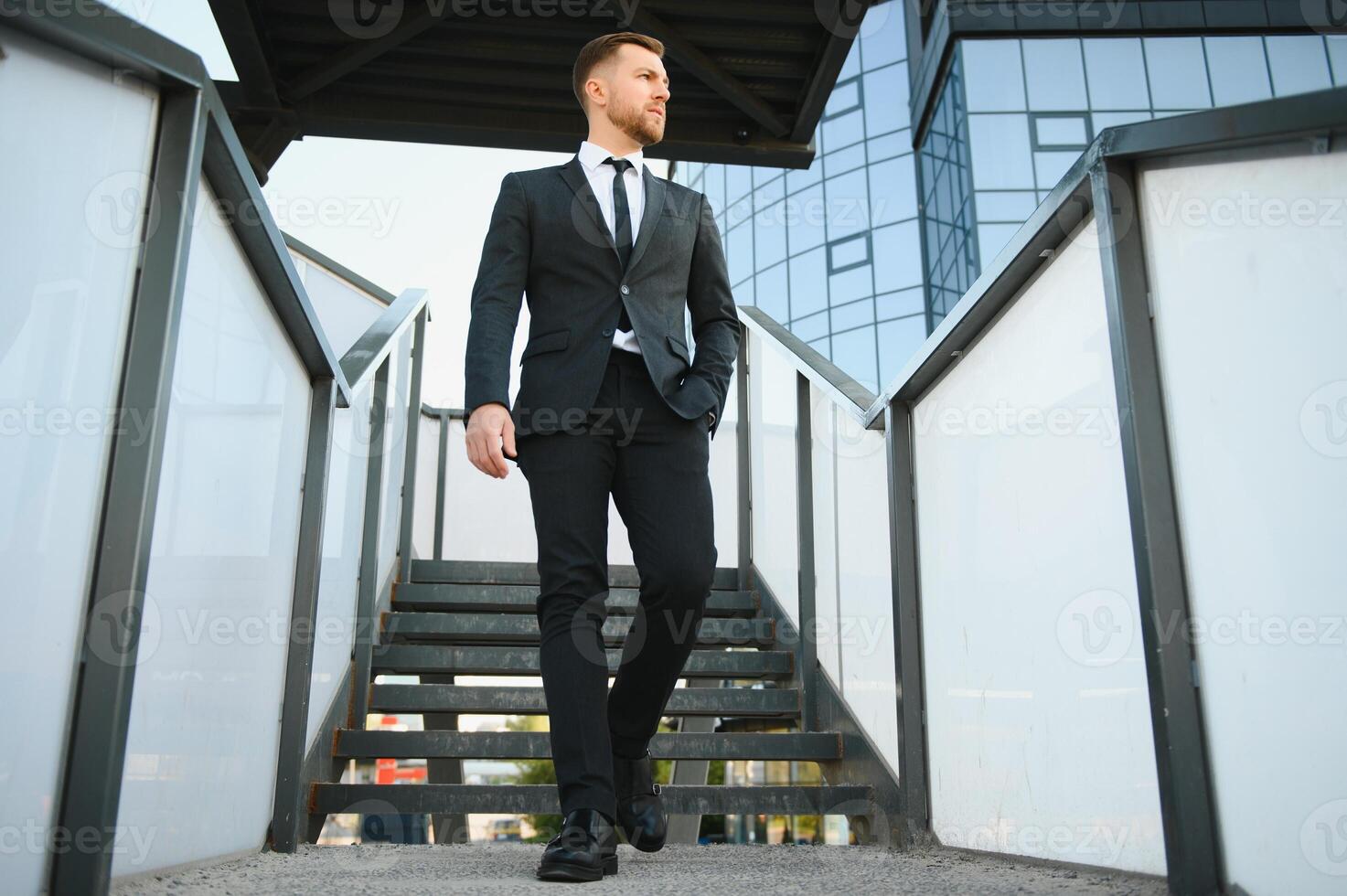 Modern businessman. Confident young man in full suit and looking away while standing outdoors with cityscape in the background photo