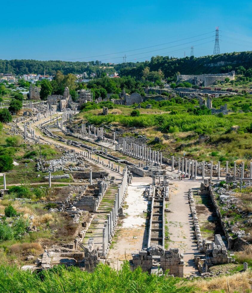 View from a height of the ancient city of Perge. Ancient city surrounded by dense green vegetation. photo
