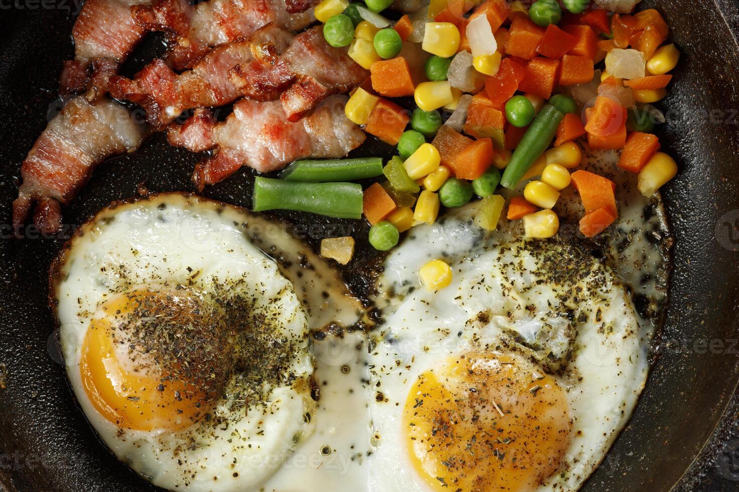 Fried eggs with vegetables in a pan. photo