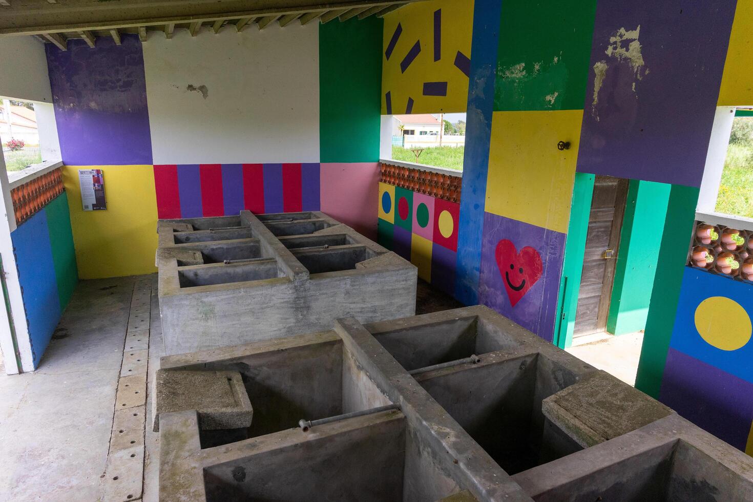 Fazendas do Cortico, Alentejo, Portugal. April 20, 2024. A rustic washhouse at fazendas do Cortico, with vibrant modern art painted on its weathered walls. photo