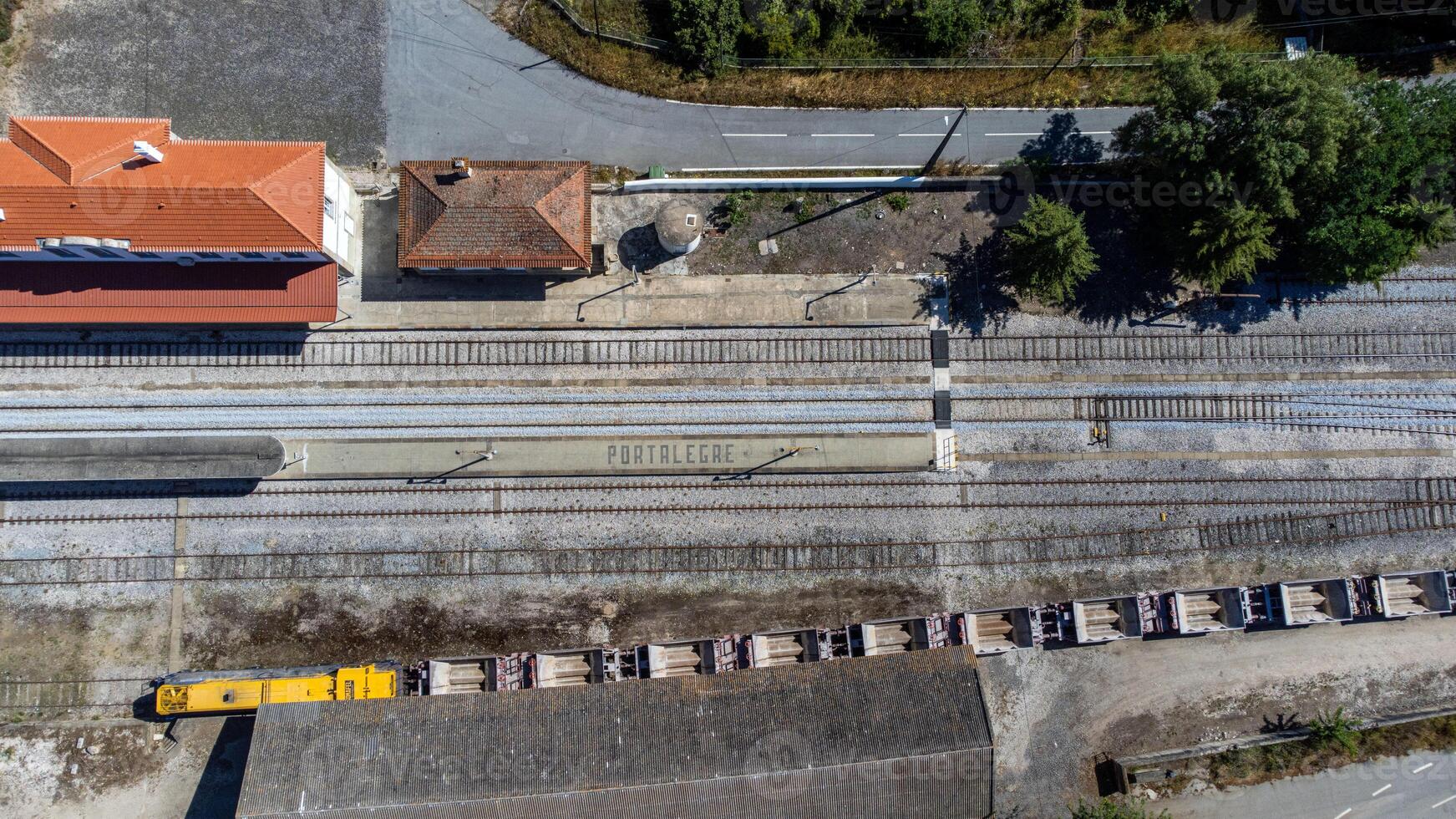 Aerial view of Portalegre railway station, featuring the word Portalegre spelled out in stone on the platform, with cargo wagons visible on the tracks. photo