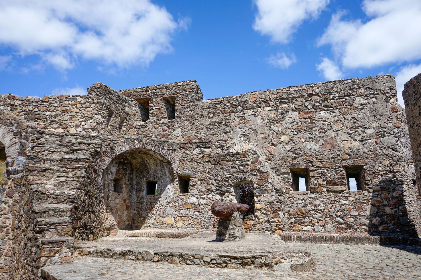 Marvao, Portugal. May 19, 2024. Battlements of Marvao Castle with old cannons pointing toward the scenic landscape, capturing history and panoramic views in a display of medieval defense architecture. photo