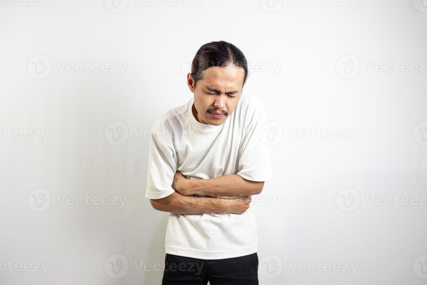 Young Asian man. suffering from severe stomach ache. isolated on white. photo