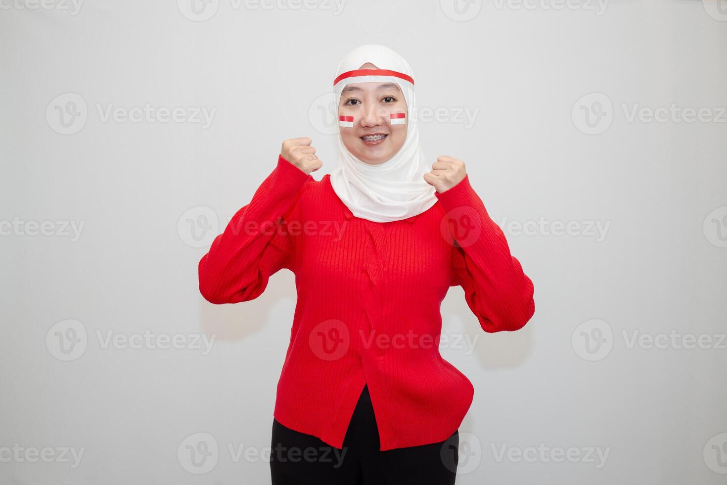 Woman in white hijab wearing red shirt. celebrating Indonesia's independence day. with clenched fists and excitement. isolation on white background. photo