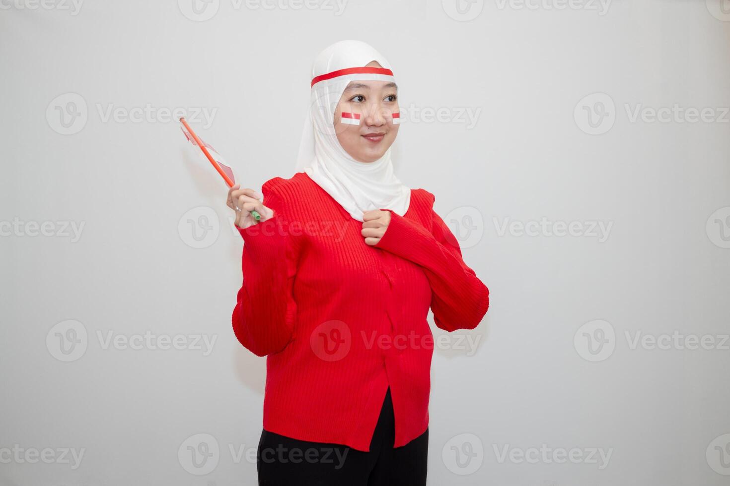 Woman in white hijab wearing red sweater. celebrating Indonesia's independence day. holding a flag and clenching his fists to his chest. isolation on white background. photo