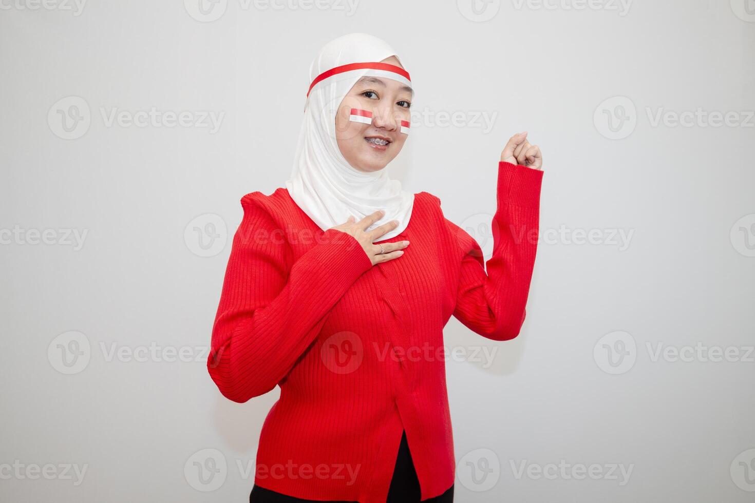 Woman in white hijab wearing red sweater. celebrating Indonesia's independence day. with his hands clenched into fists. isolation on white background. photo