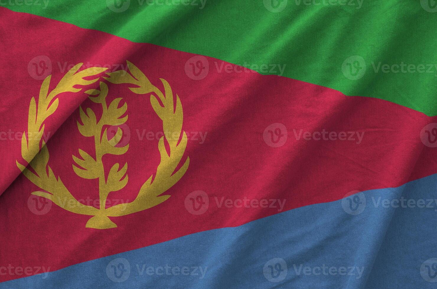 Eritrea flag depicted on folded wavy fabric of old cloth photo