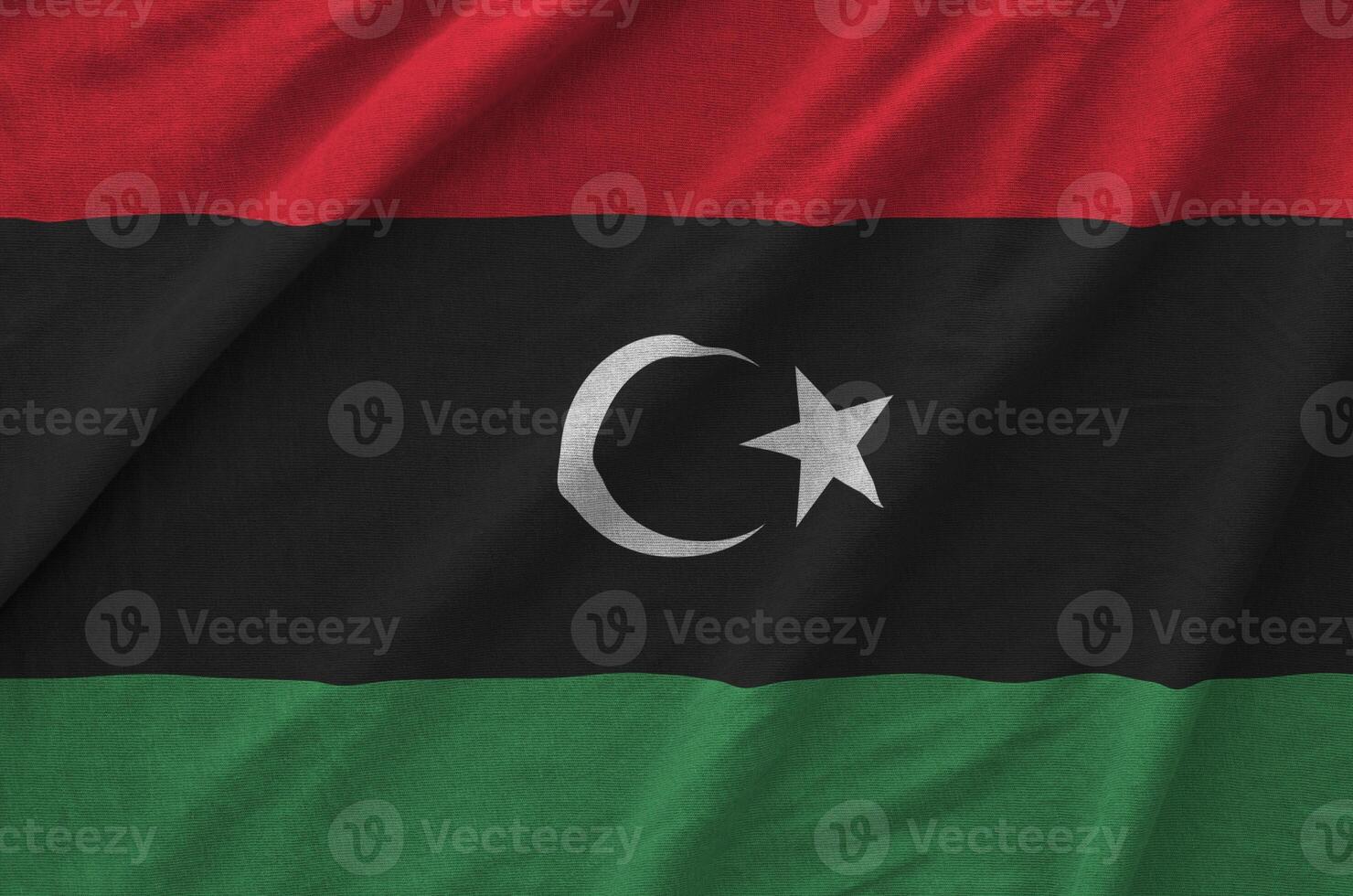 Libya flag depicted on folded wavy fabric of old cloth photo