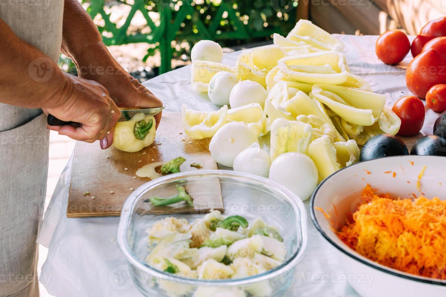 The hands of an old woman cut a salad of various fresh vegetables. Organic food, vegetarianism. photo