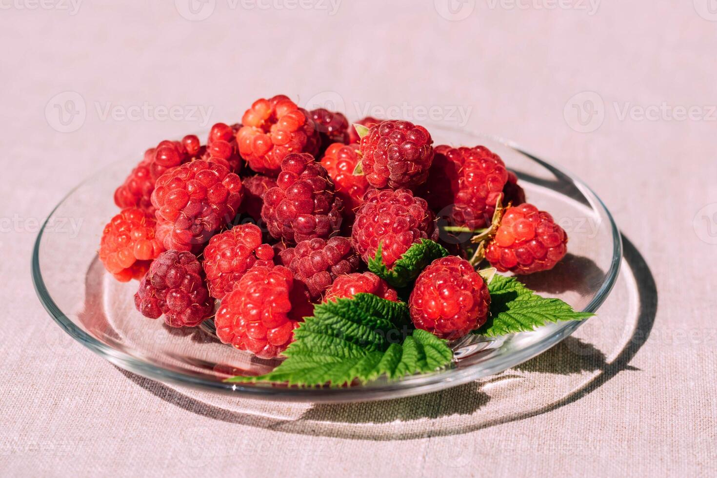 Red raspberry in a plate on the kitchen table, summer seasonal food. Background of fruity ripe berries photo