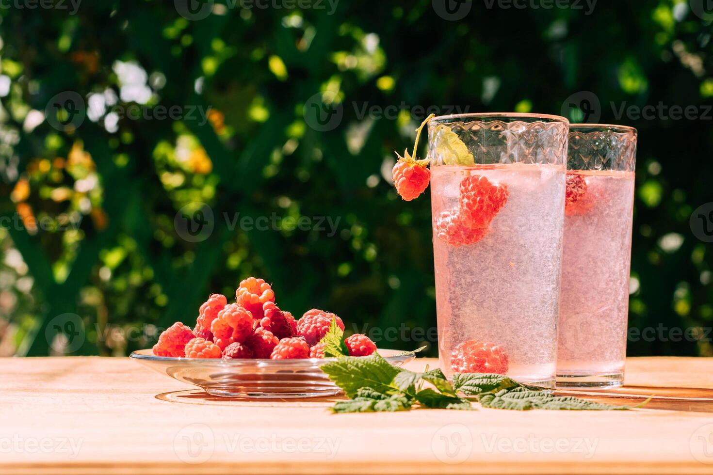 Drink from ripe red raspberries in two transparent glasses, summer background. Summer seasonal freshly refreshing drink photo