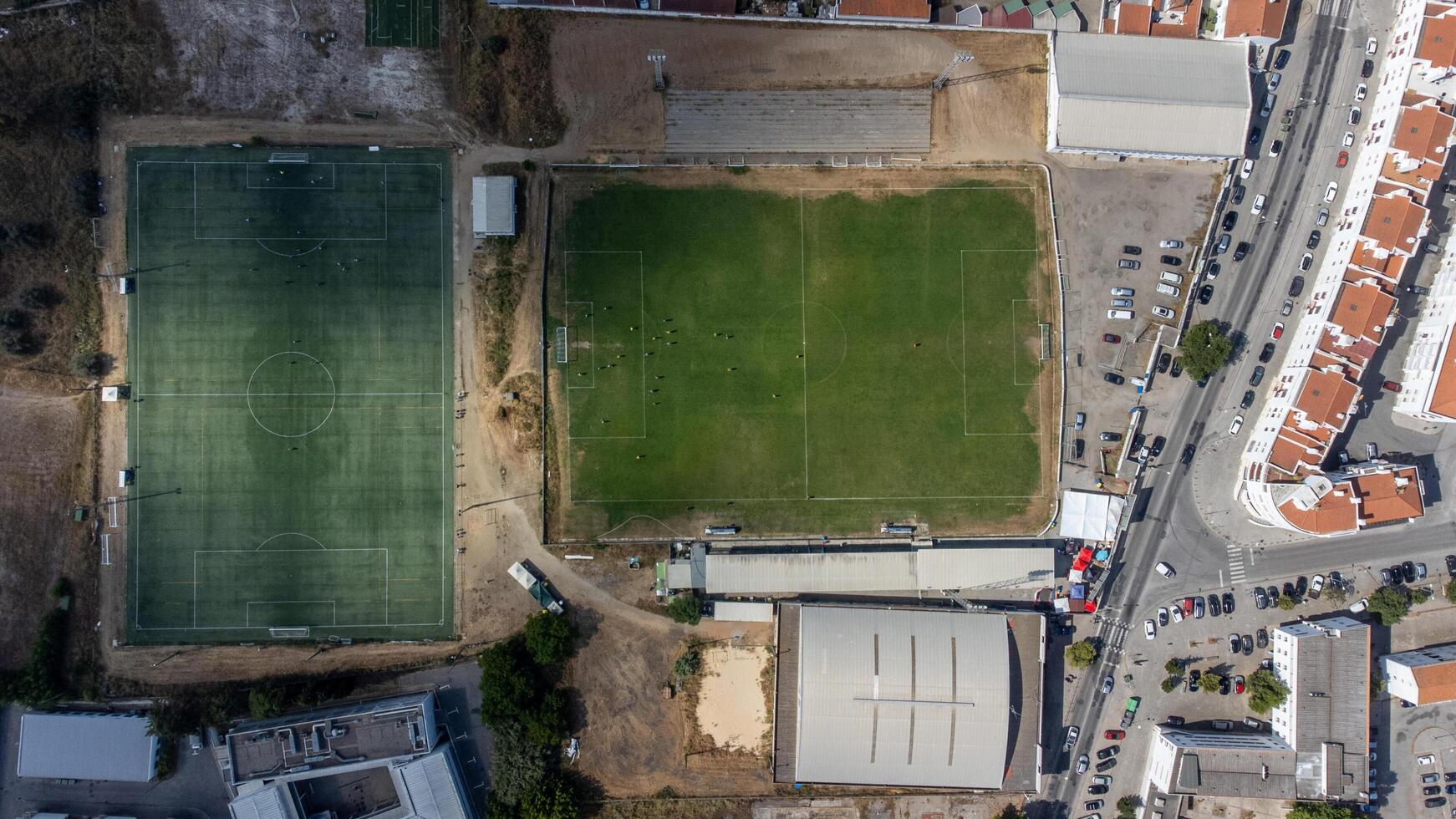 Aerial view of a football sports complex with multiple fields, stadium seating, training facilities, and lush green surroundings, perfect for athletic events and outdoor activities. photo
