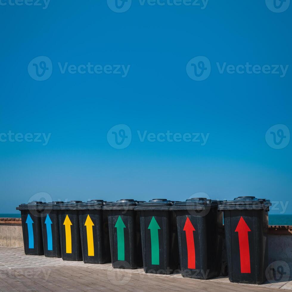 Black plastic garbage cans near the sea. Containers for different rubbish on a background of blue sky. Garbage sorting for further processing. photo