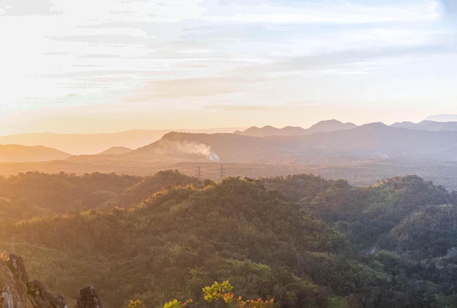 The stunning view from a tourist's standpoint as they go down a hill on a foggy trail with a hill and a background of a golden sky in Forest Park, Thailand. Rainforest. Bird's eye view. Aerial view. photo