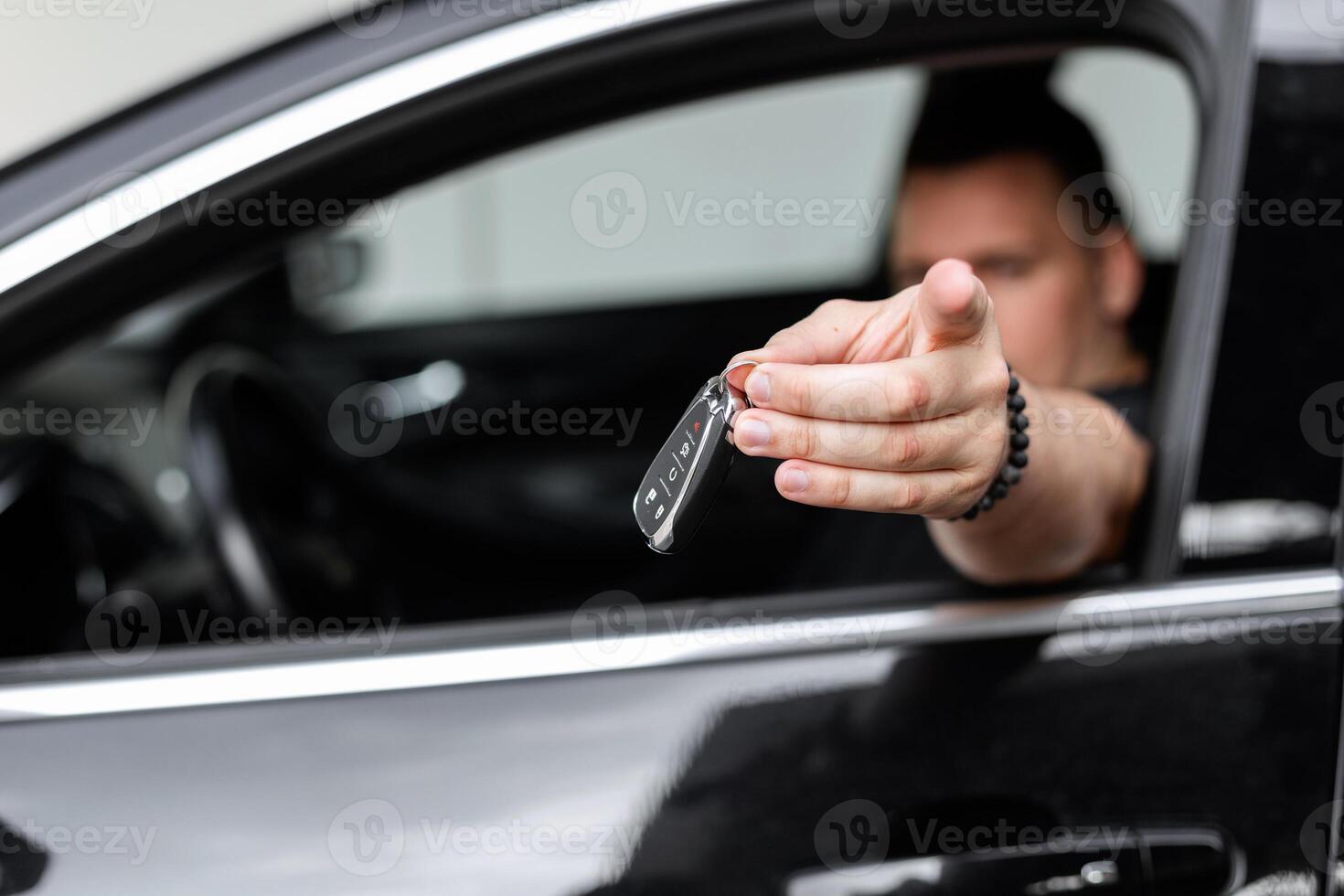 Cool happy man manager sits in the car and holds the car keys. Gives the keys, Car rental and purchase photo