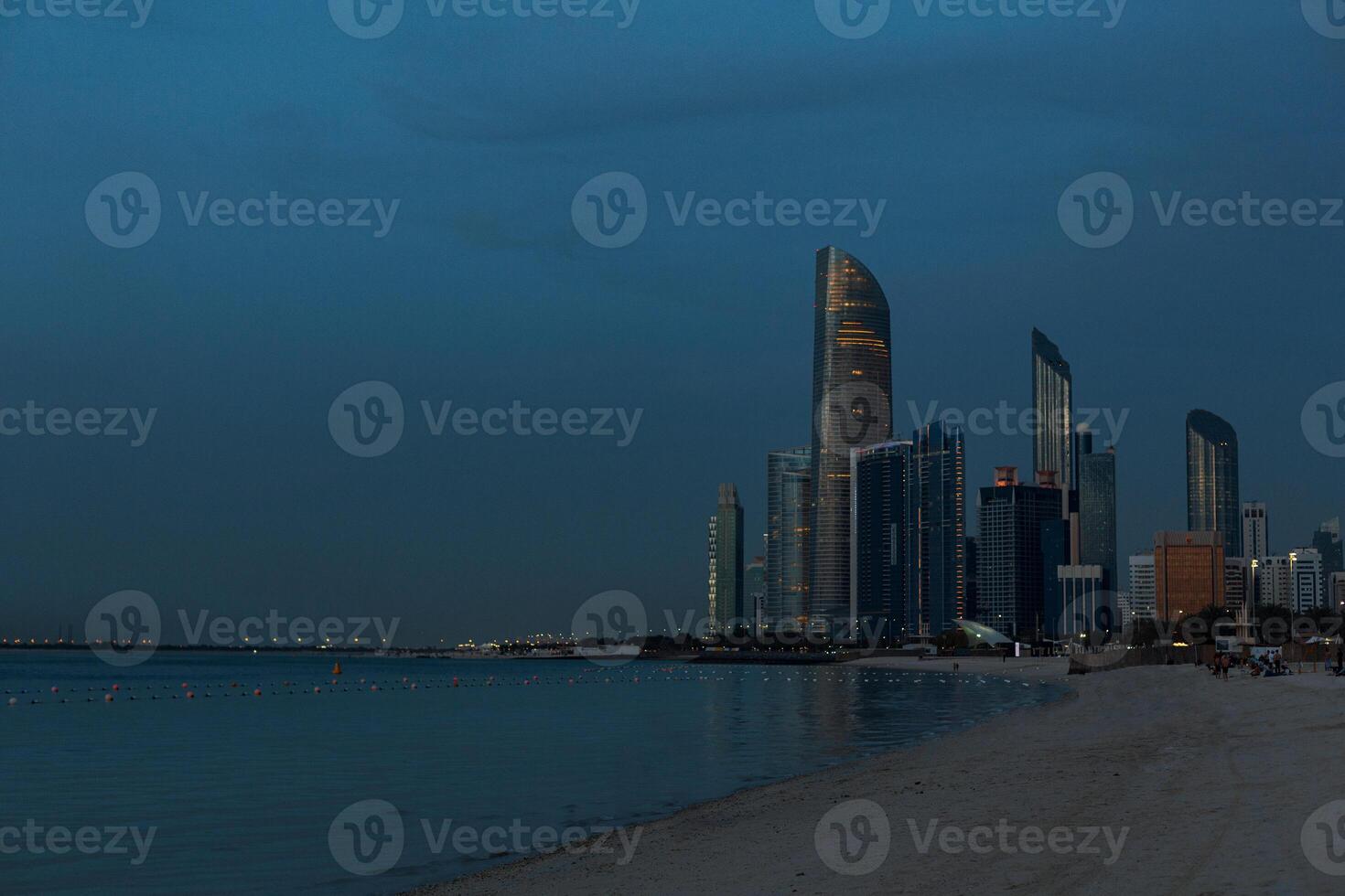 Public beach with high-rises and buildings of the city of Abu Dhabi, UAE late evening after sunset photo