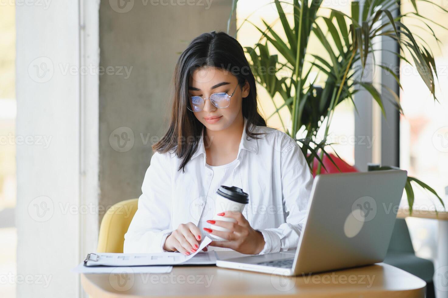 Freelance, business and e-commerce concept. Creative enthusiastic female journalist writing new article, typing on laptop, smiling, write-down project ideas, sit cafe, drink coffee working remote photo