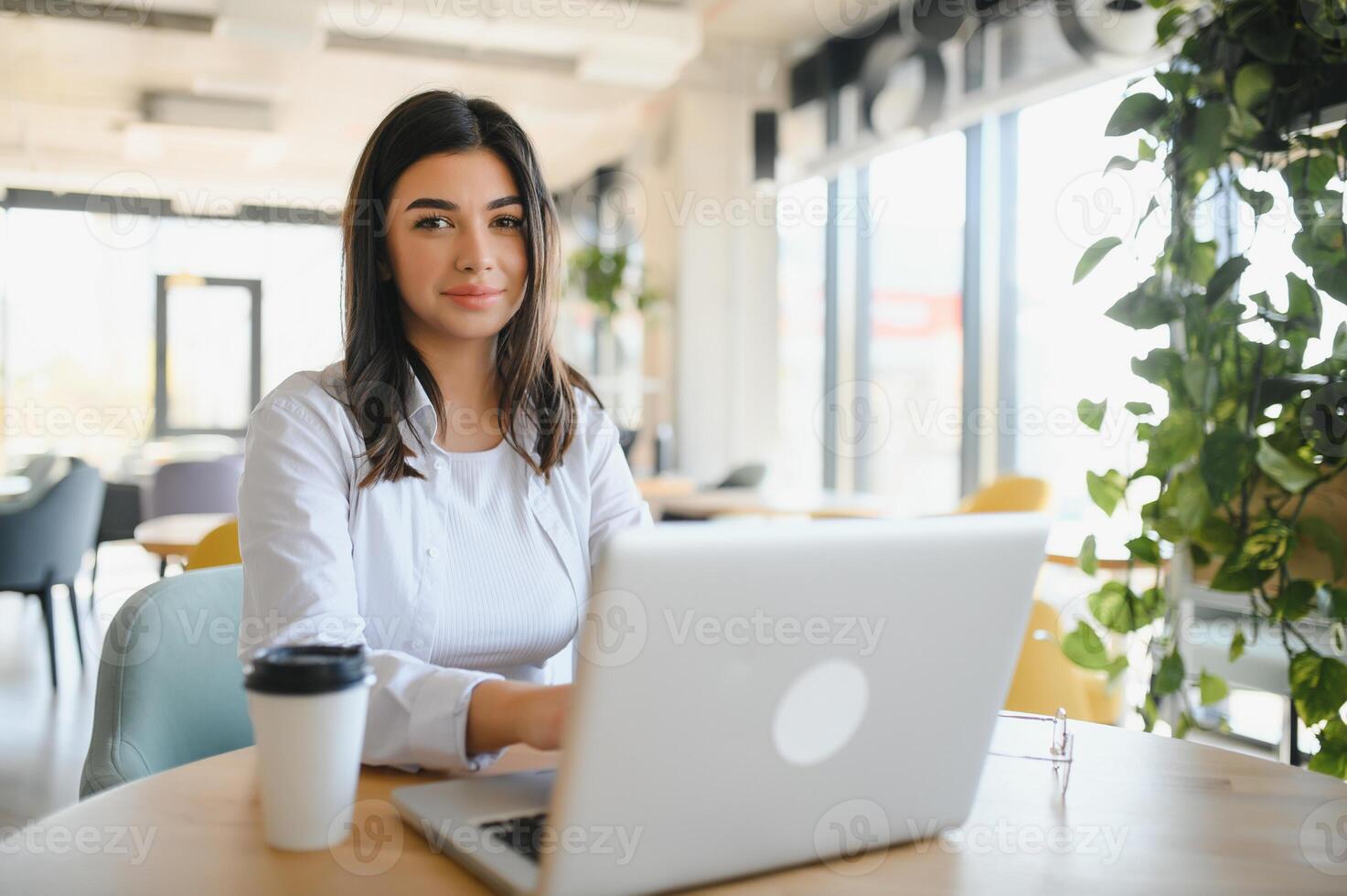 Freelance, business and e-commerce concept. Creative enthusiastic female journalist writing new article, typing on laptop, smiling, write-down project ideas, sit cafe, drink coffee working remote photo