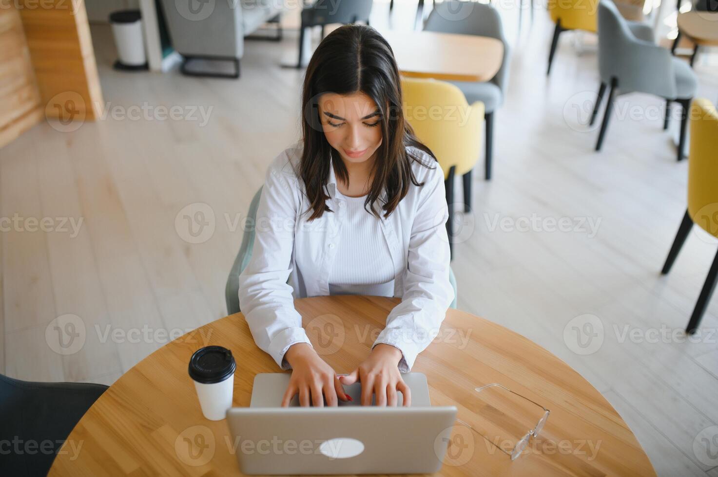 Beautiful Caucasian woman dreaming about something while sitting with portable net-book in modern cafe bar, young charming female freelancer thinking about new ideas during work on laptop computer photo
