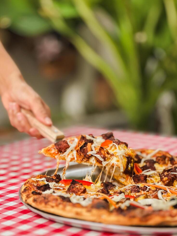 Woman hand takes a slice of pizza with spatula on table. photo