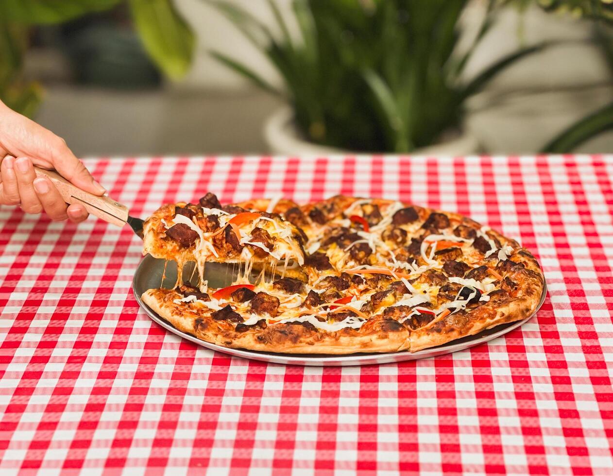 Woman hand takes a slice of pizza with spatula on table. photo
