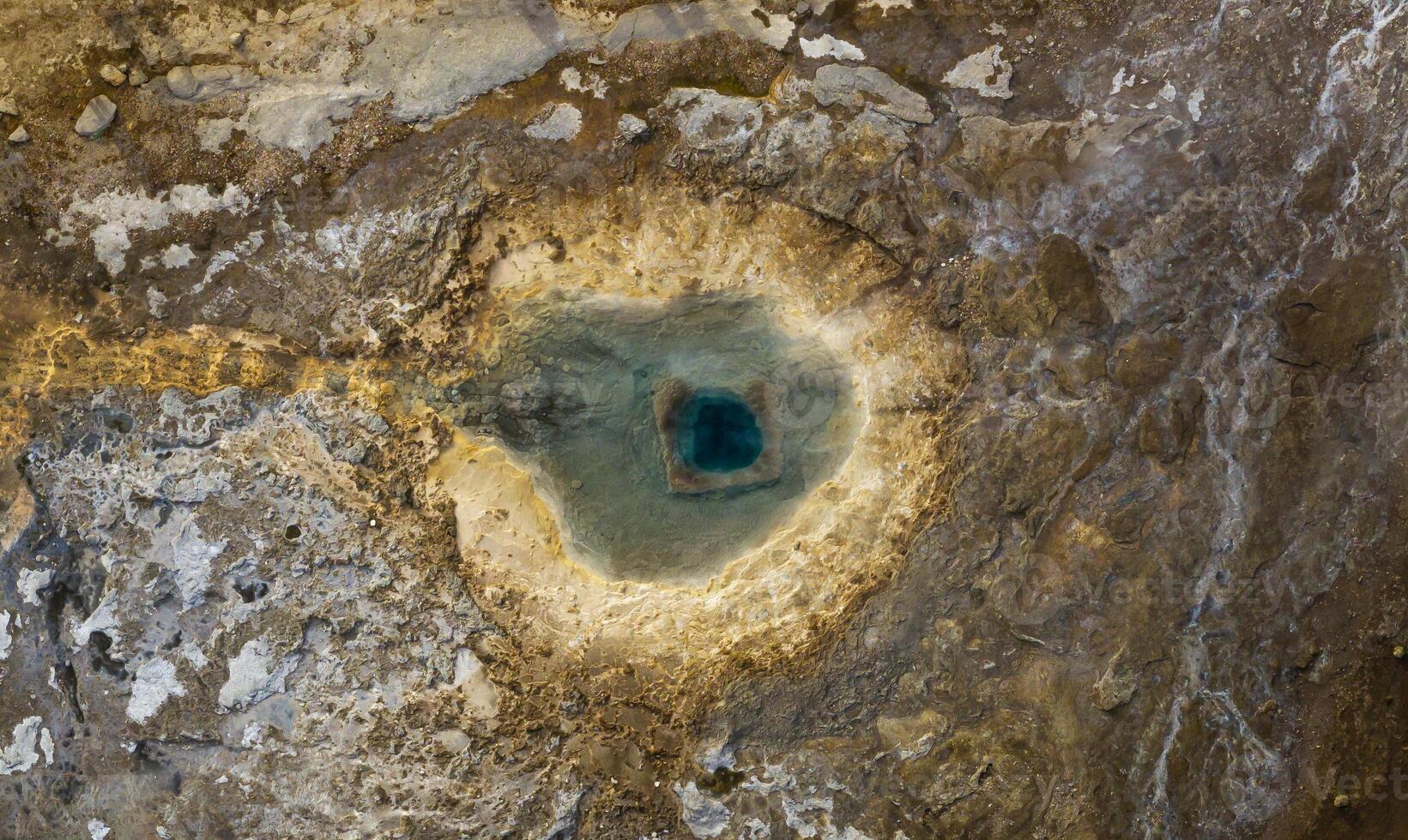Aerial view of a geothermal hot spring in Strokkur Iceland, showcasing the unique geological formations and vibrant blue water. photo