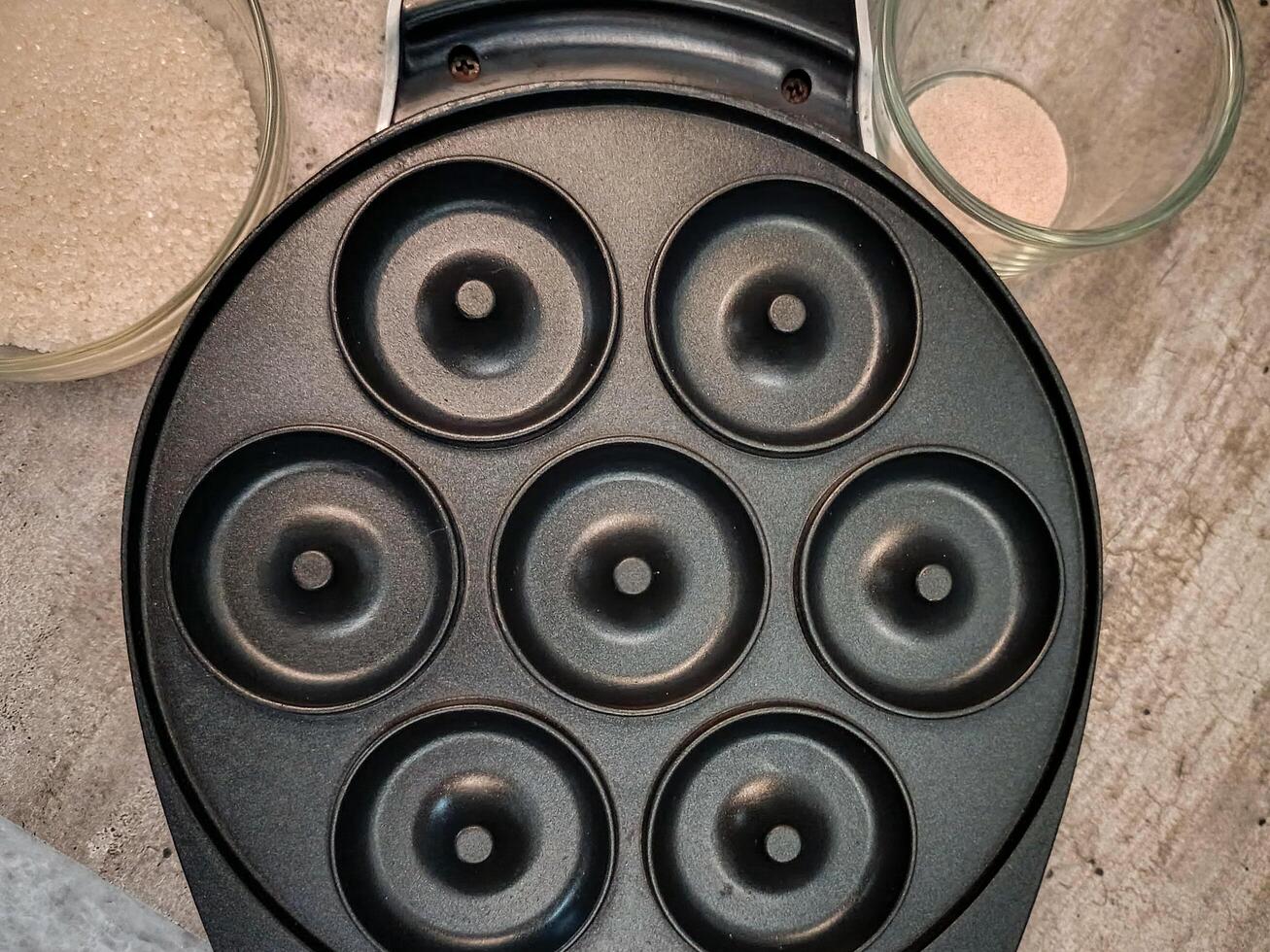 The electric donut maker is on a gray marble textured table photo