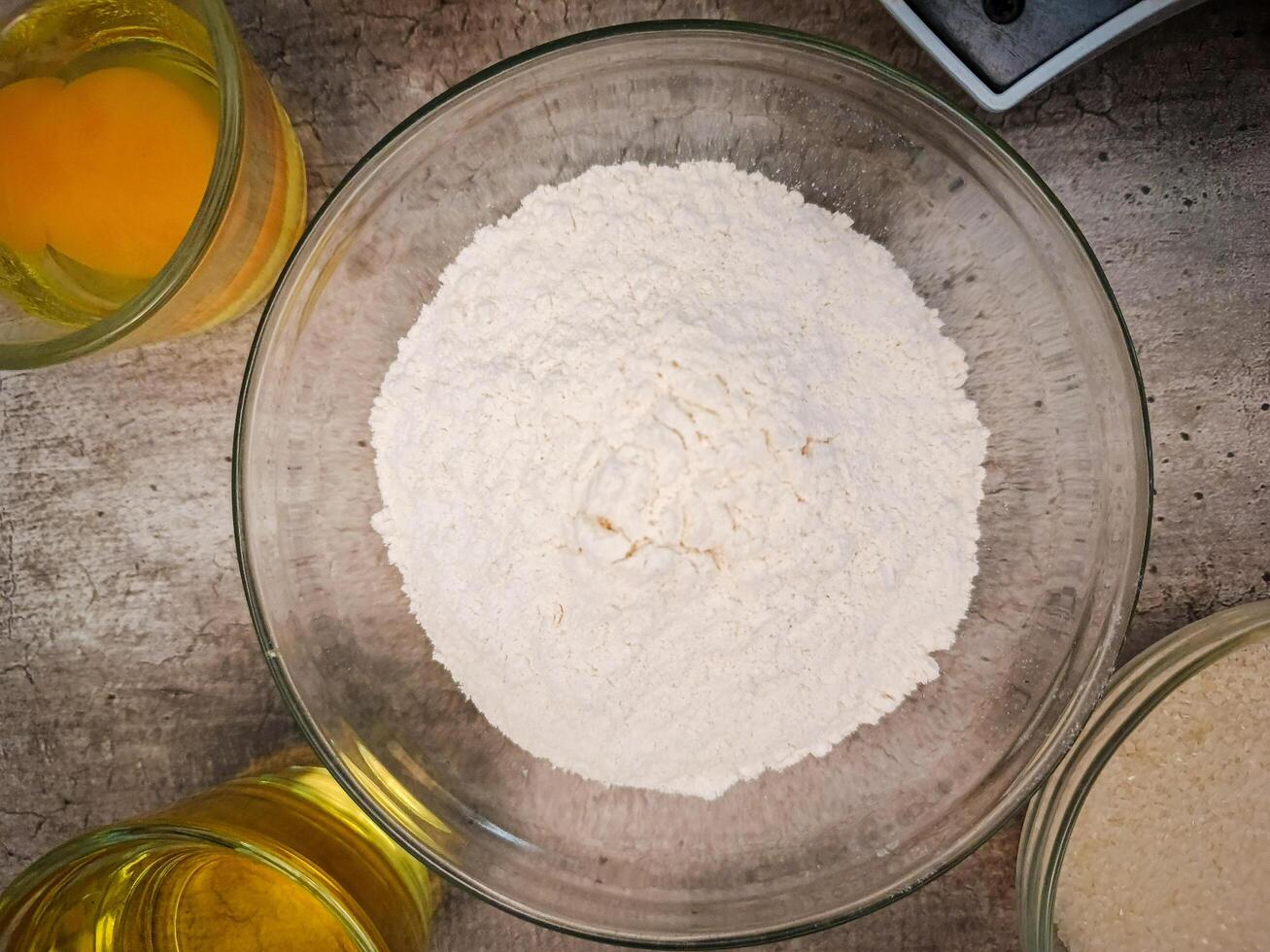preparation for making cakes with flour in a glass bowl in the middle of other ingredients photo