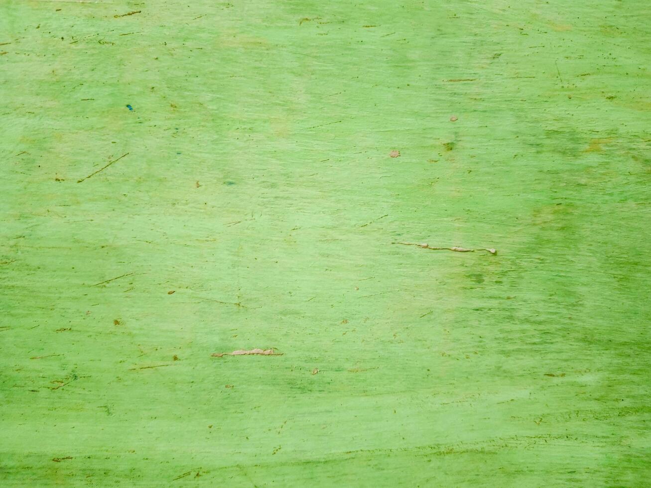 The background surface is textured wood with green tones, showing scratches and scuffs. photo