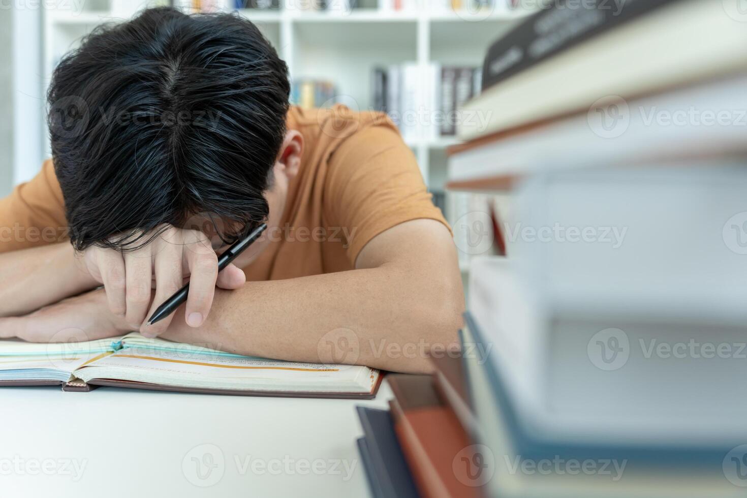 Asian student man have anxiety because of exams, male prepare for test and learning lessons in the library. stress, despair, haste, misunderstanding reading, discouraged, expectation, knowledge, tired photo