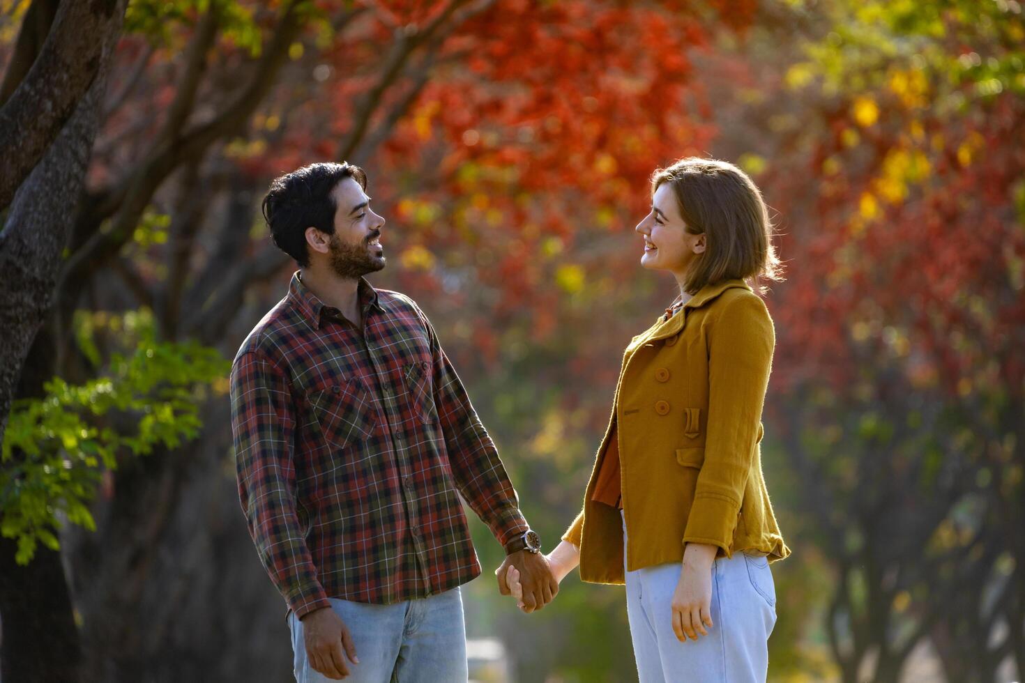 Happy caucasian couple walking together in public park during autumn with maple and beech tree for fall color travel destination and family happiness photo
