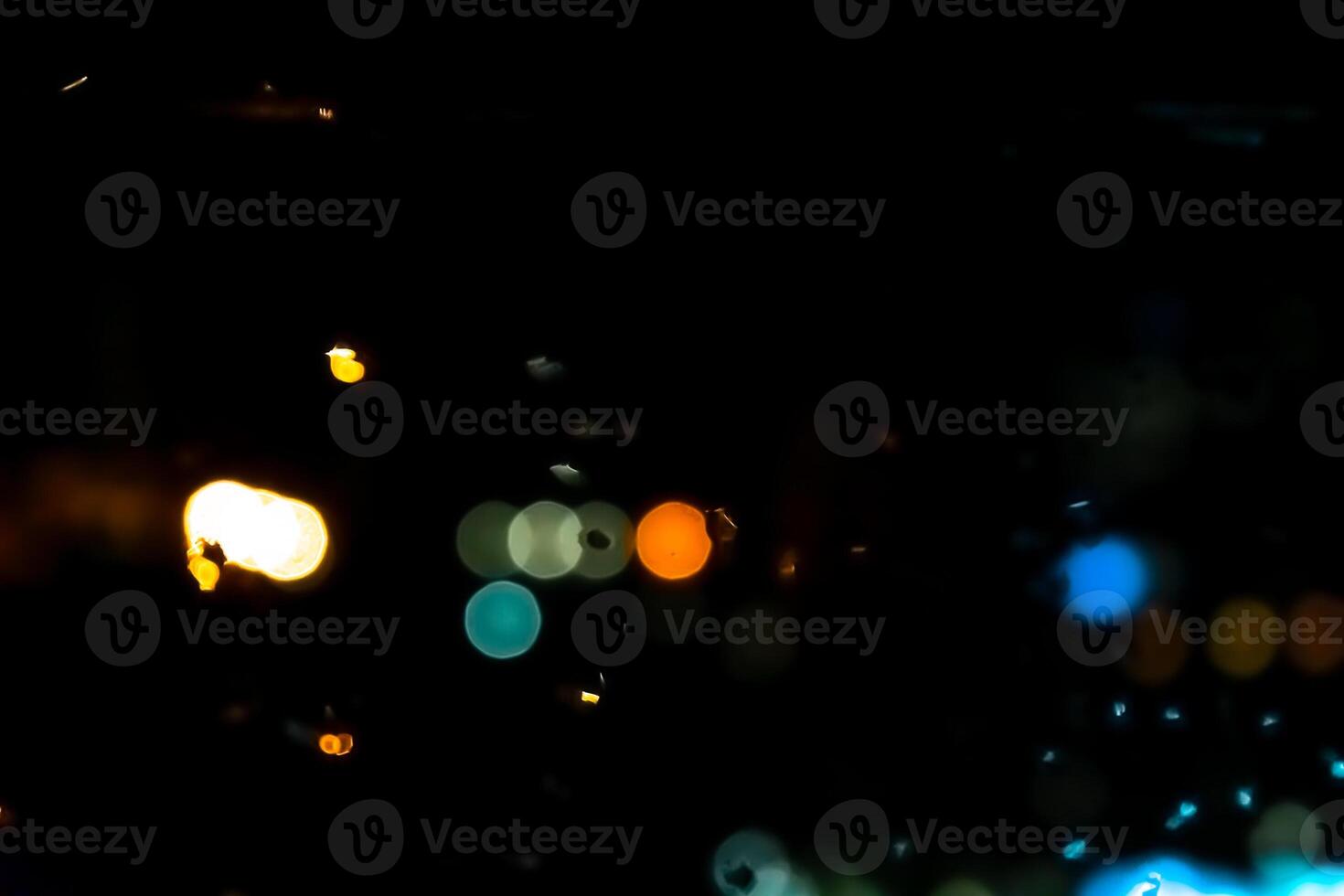 Mesmerizing urban bokeh through raindrops on window glass creating a cozy atmosphere. The glitter of bokeh city lights through the window. photo