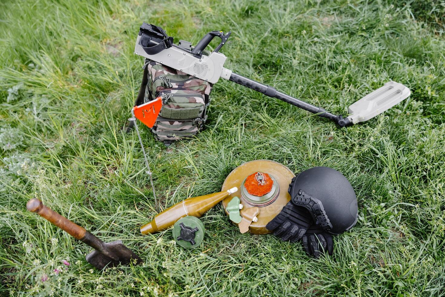 Explosive devices and a metal detector lie on the background of a forest massif. Equipment for demining the territory photo