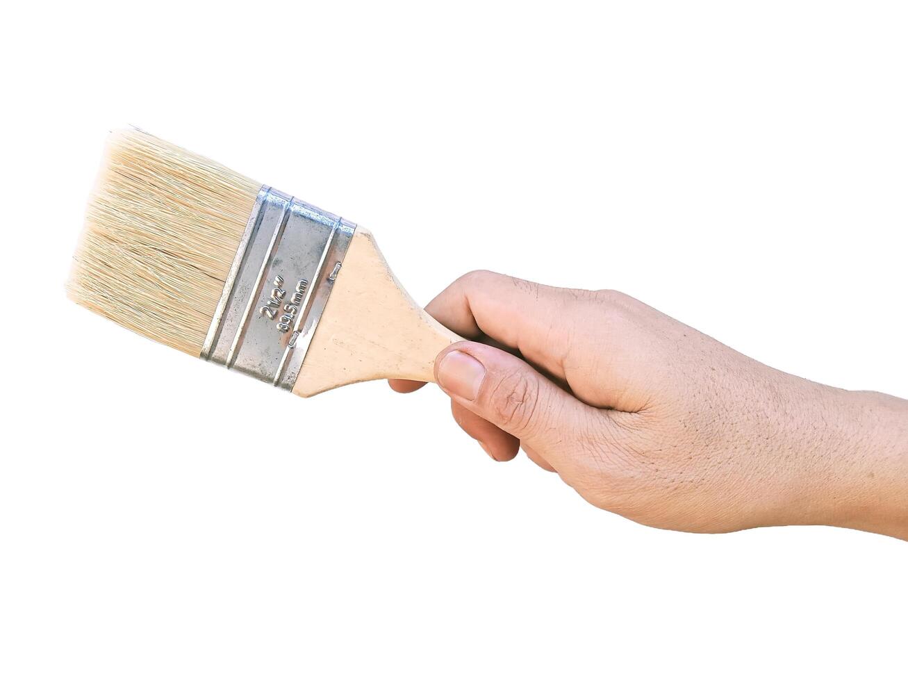 Hand holding yellow paint brush, close-up horizontal view, white background photo