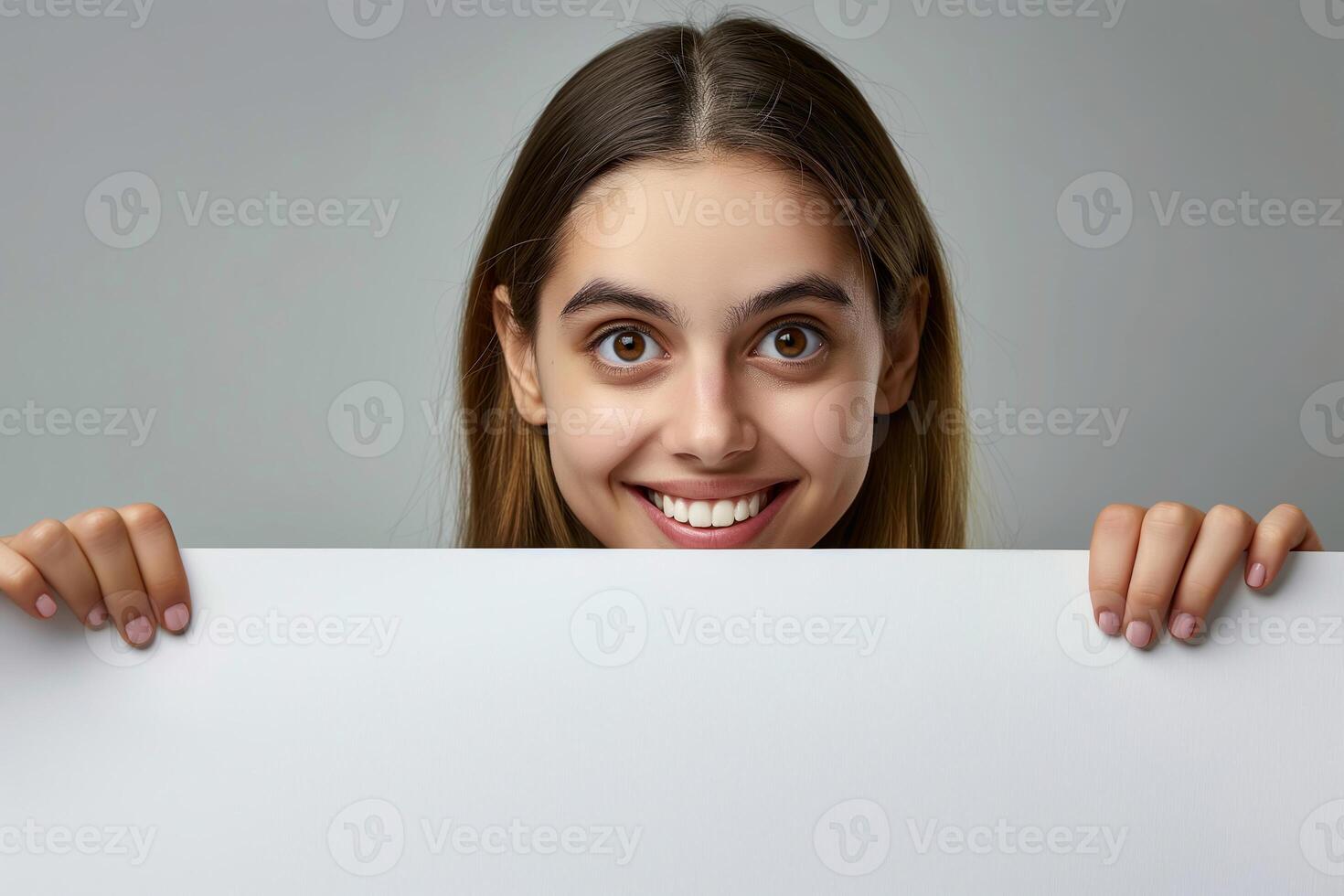 Woman Holding White Blank Copy Space Poster With Smiling Expression On Grey Background For Advertisement, Marketing, And Communication Design Concepts, Suitable For Holiday Greeting Cards photo