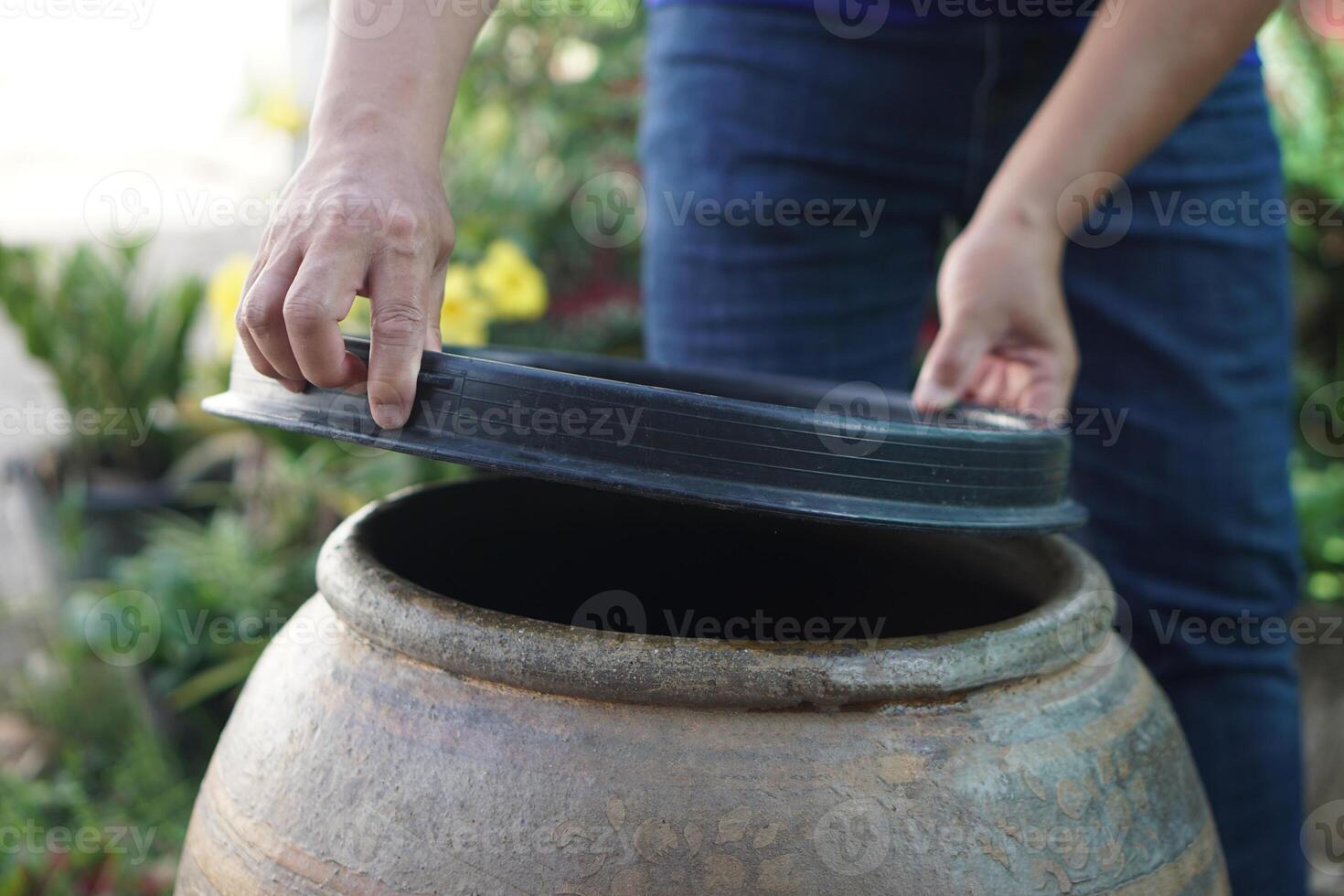 Closeup hands hold lid to cover water jar to protect from mosquitoes to breed inside or other insects or dust go into water. Concept, campaign to stop mosquitoes cycle to lay eggs in water container photo