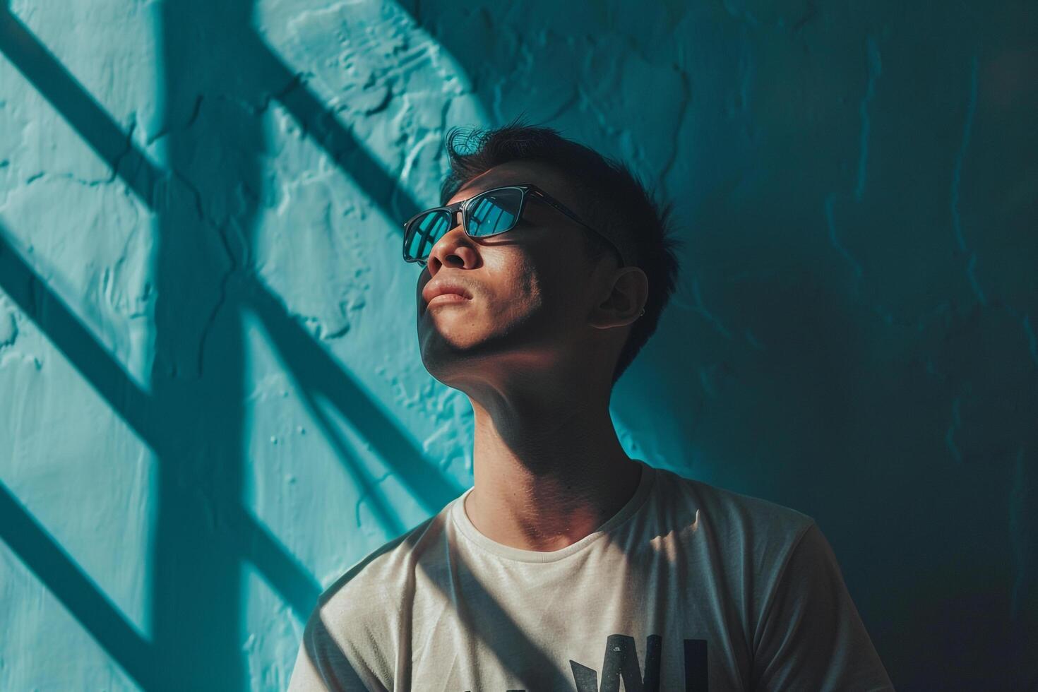 Male fashion model in an aqua blue graphic tee set against a straightforward background creating a relaxed portrait that highlights casual Males fashion photo