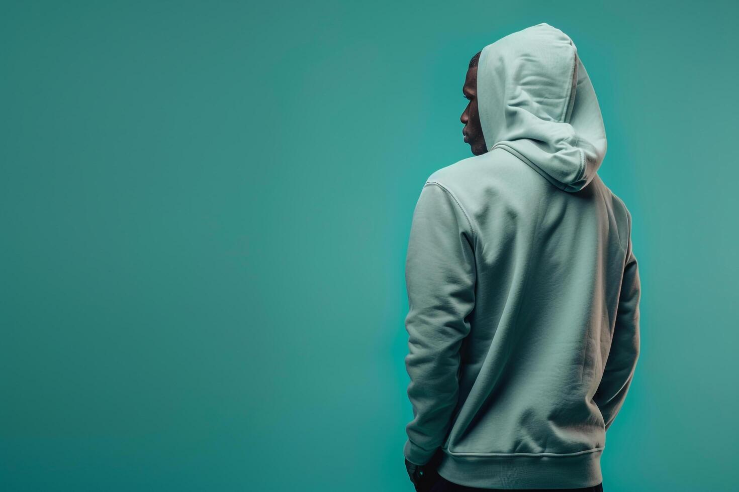 Fashionable male model in a hoodie with a light teal background captured for a casual yet stylish portrait that emphasizes contemporary trends and modern flair photo