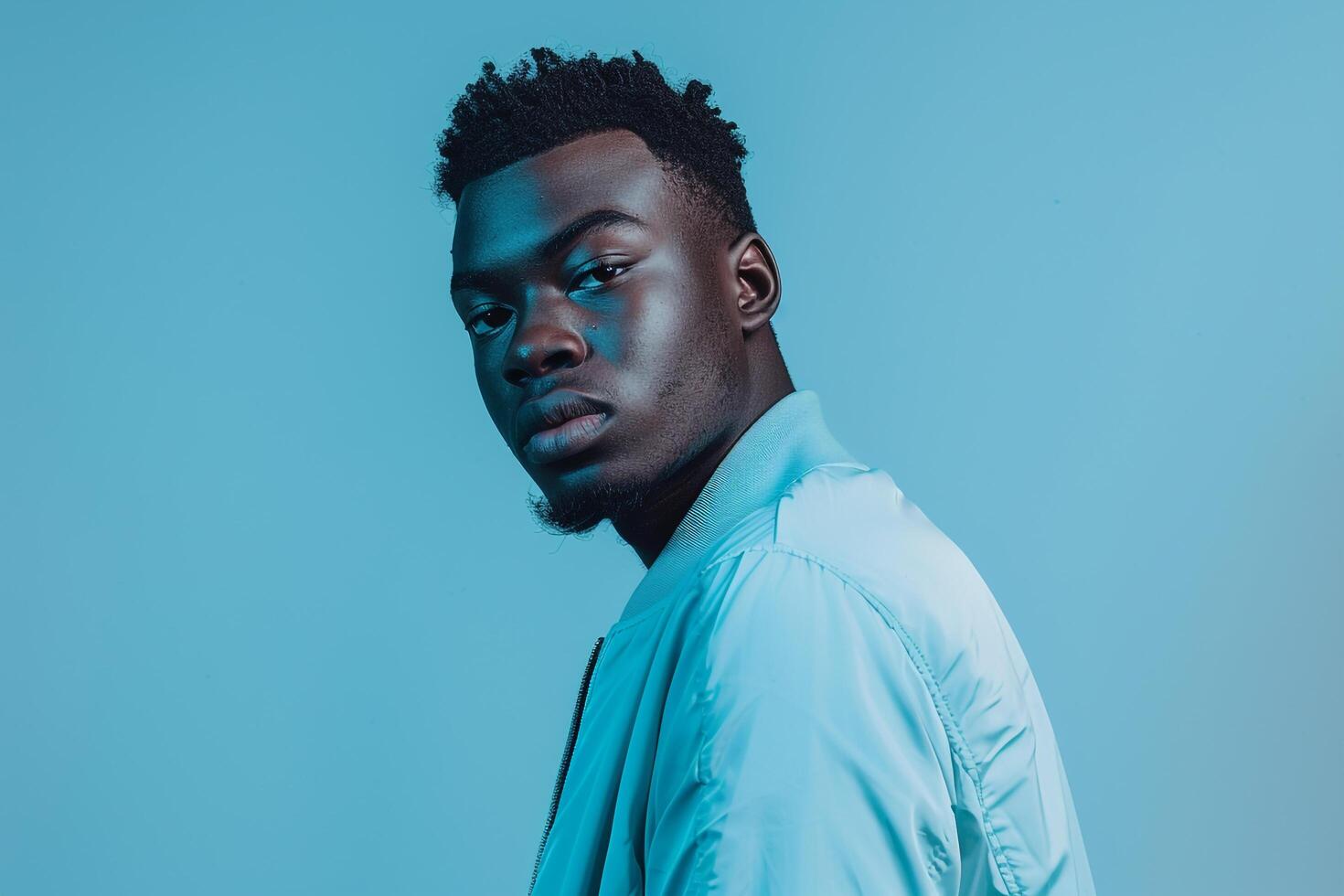 Fashionable male model in a zip up jacket with an icy blue background chic portrait showcasing trendy and modern Males outerwear photo