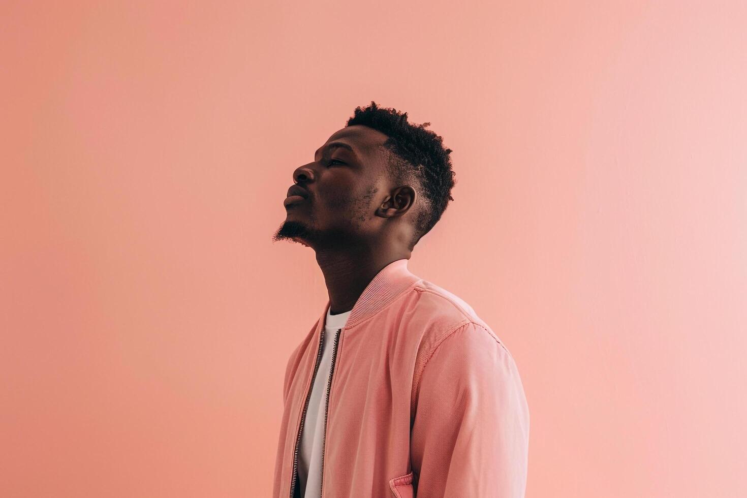 Fashionable male model in a zip up jacket with a peach pink background highlighting a modern and stylish appearance with a chic fashion sense photo