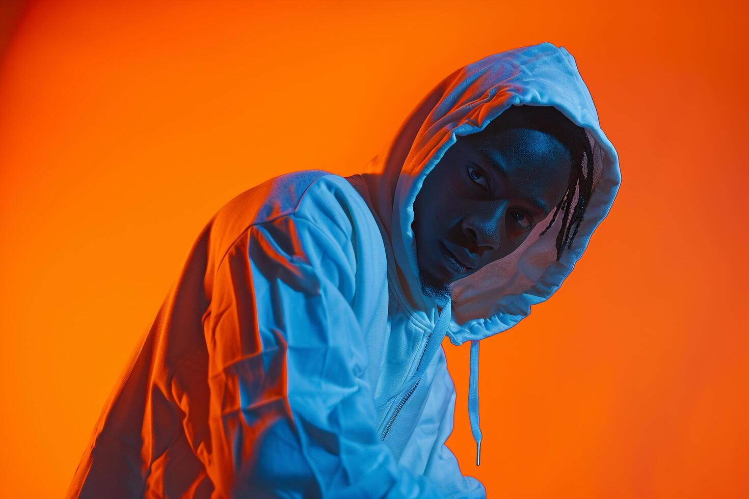 Stylish male fashion model in a hoodie with a neon orange background featuring an energetic lifestyle and stylish fashion portrait in casual Male s wear photo
