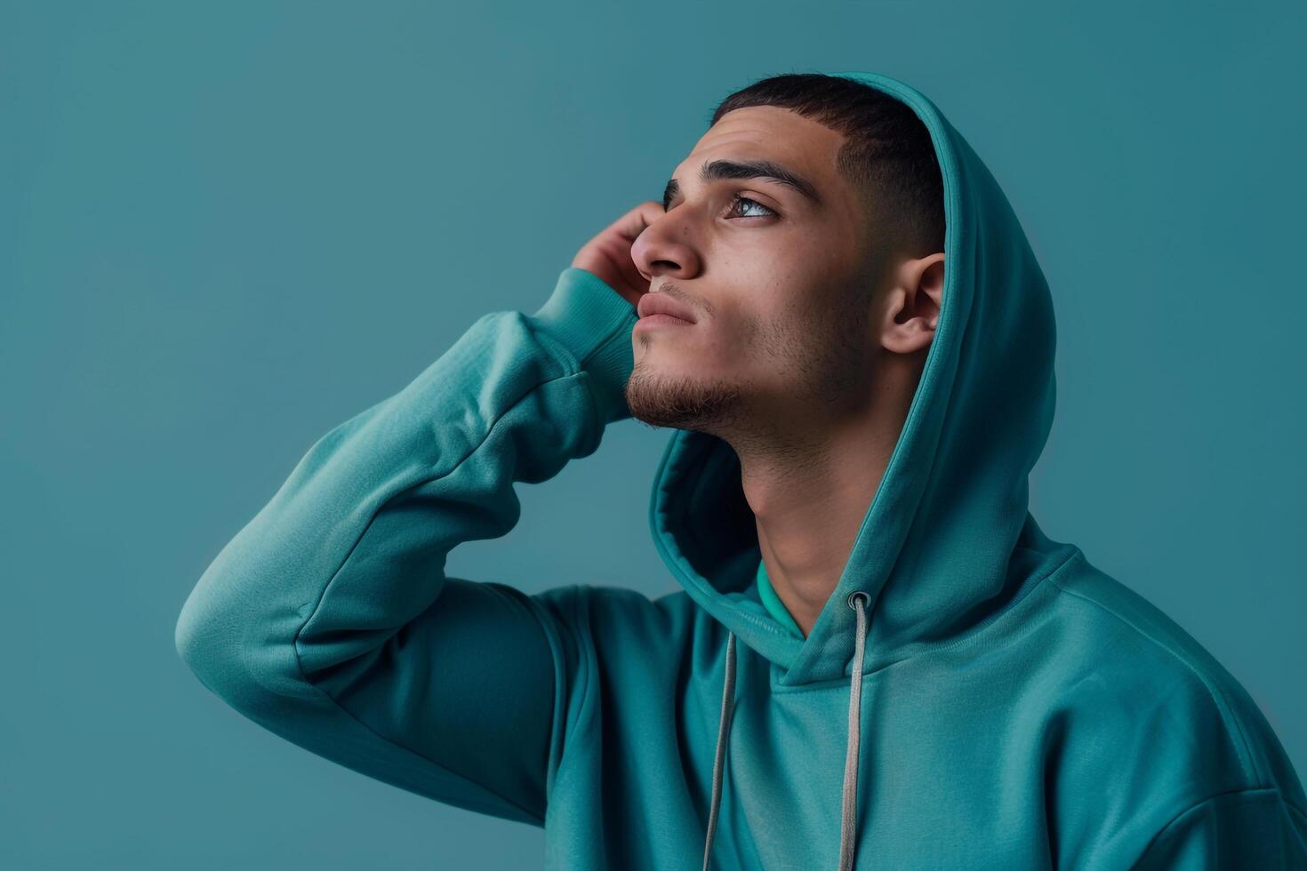 Fashionable male model in a hoodie with a light teal background emphasizing a serene lifestyle and modern fashion portrait for Male photo