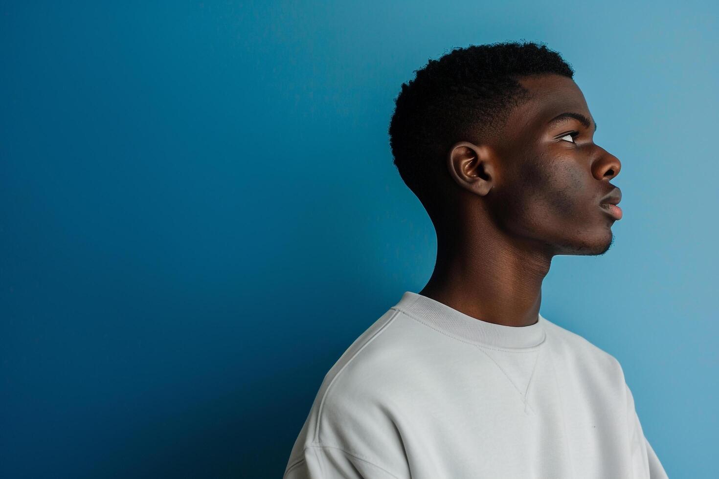 Trendy male fashion model in a sweatshirt with an electric blue background showcasing a stylish lifestyle and modern fashion portrait photo