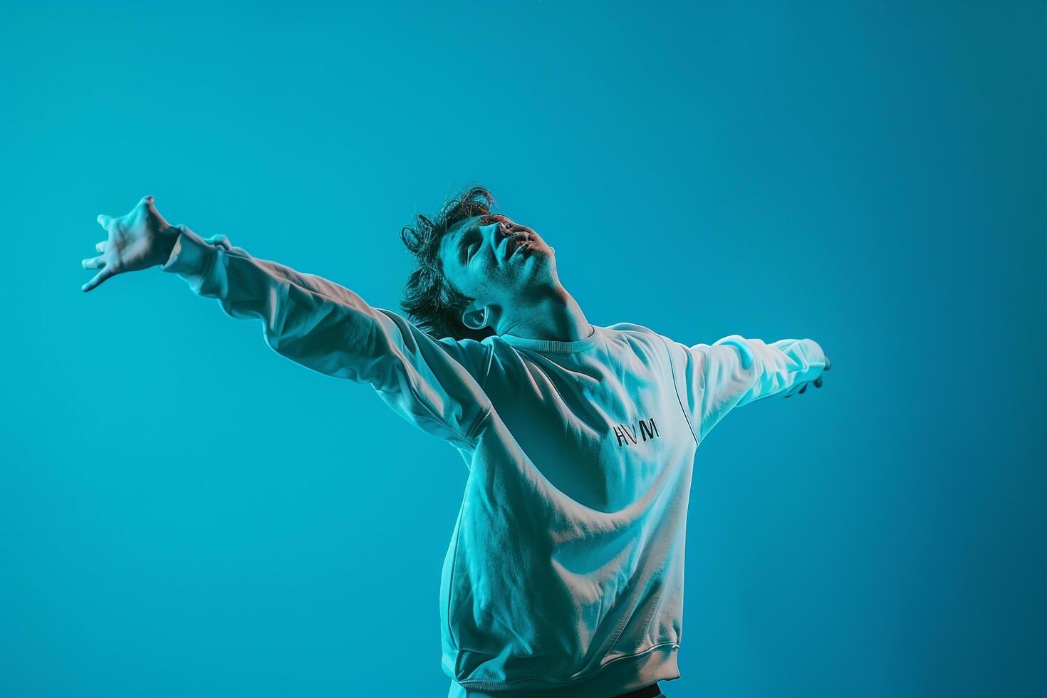 Dapper male model in a sweatshirt with an aqua blue background emphasizing modern lifestyle and fashionable portrait photo
