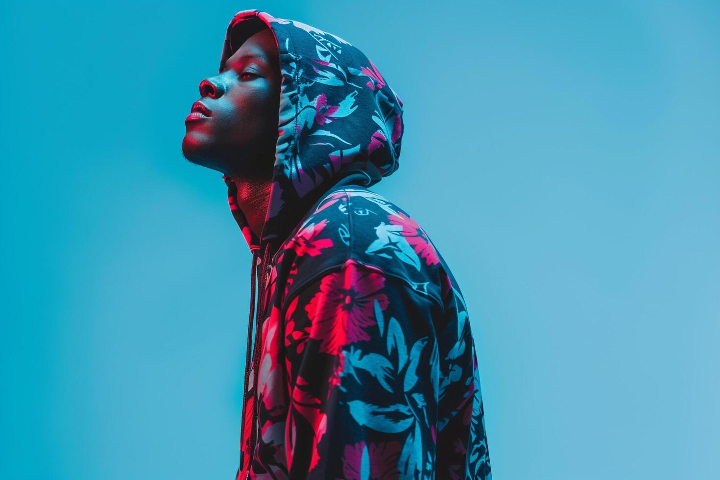 Handsome male model in a printed hoodie with an electric blue background showcasing trendy lifestyle and contemporary fashion portrait photo