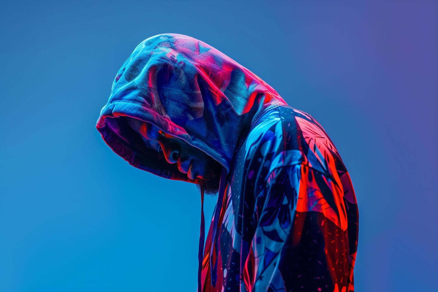 Fashionable male model in a printed hoodie with an electric blue background emphasizing stylish lifestyle and contemporary portrait photo